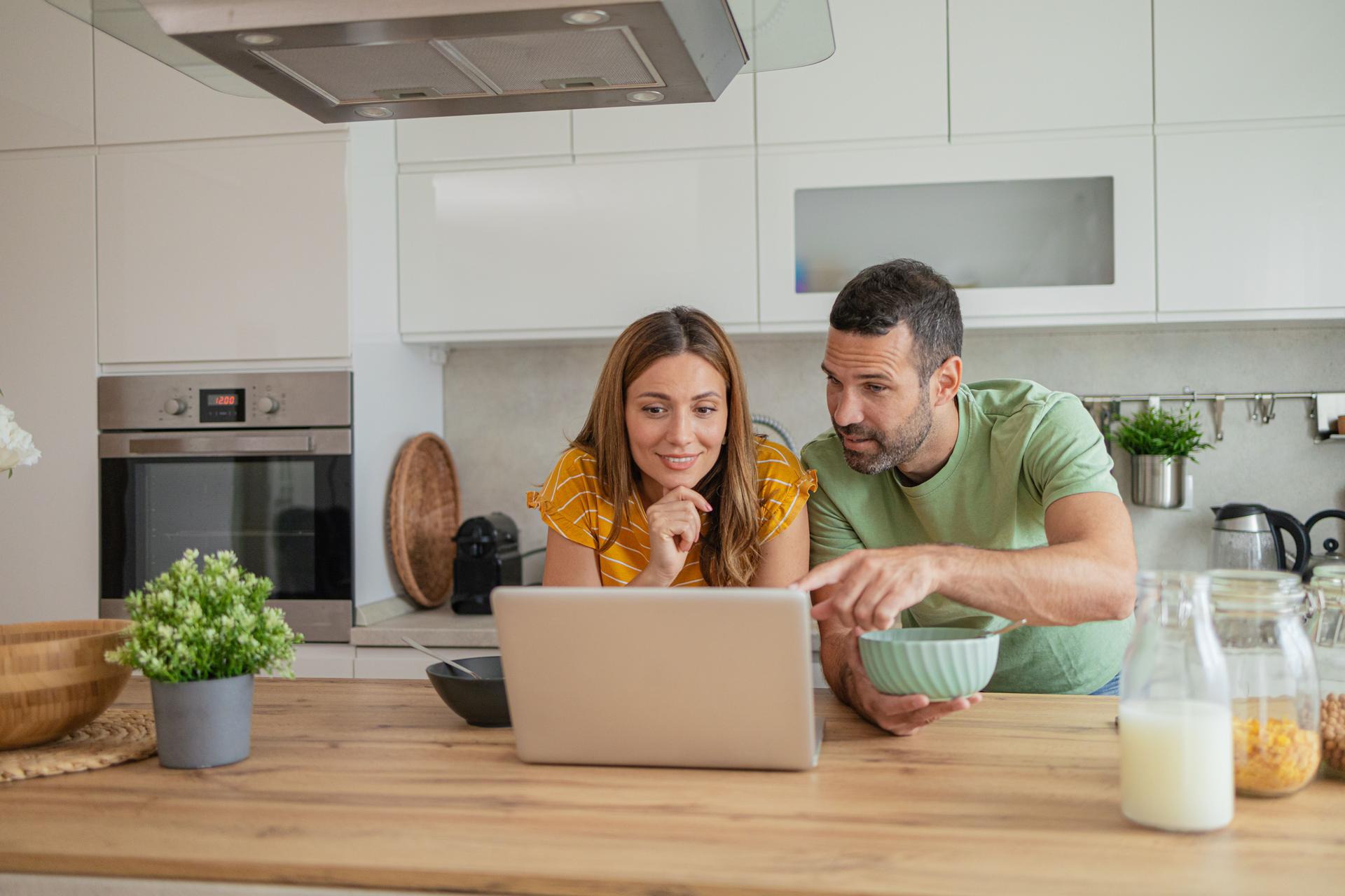 Happy couple at home booking a trip online